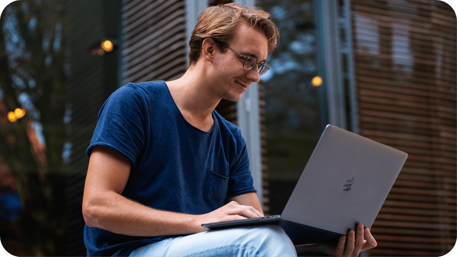 A man using a laptop while sitting casually outdoors